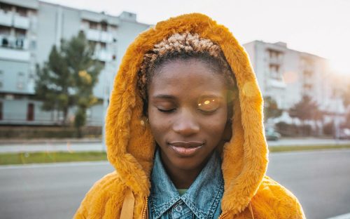 Teenage girl portrait wearing a yellow coat with eyes closed.